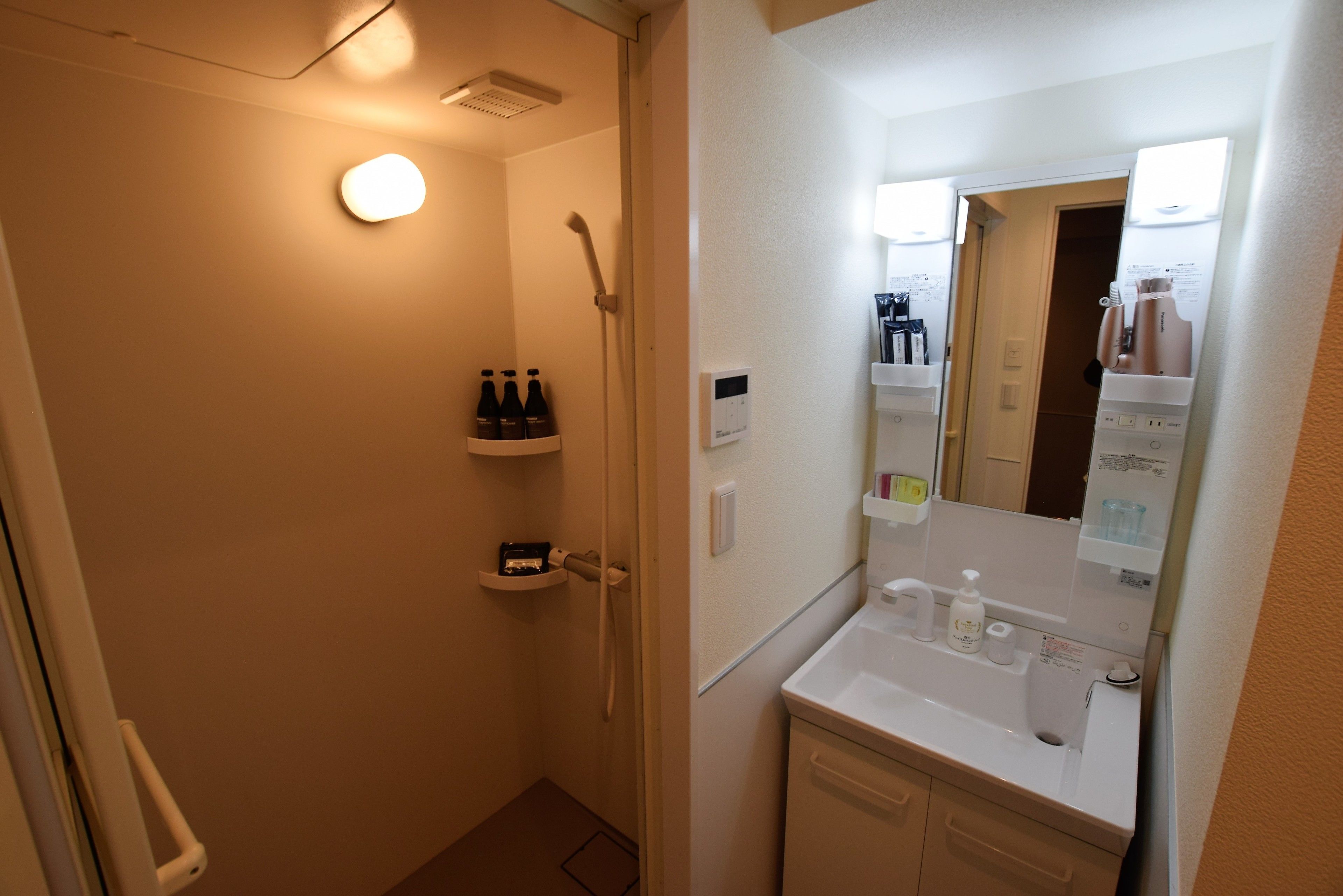 A bathroom with a shower, a sink with a mirror, and a shelf with toiletries.