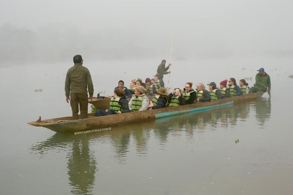 A long boat with passengers on a foggy day.