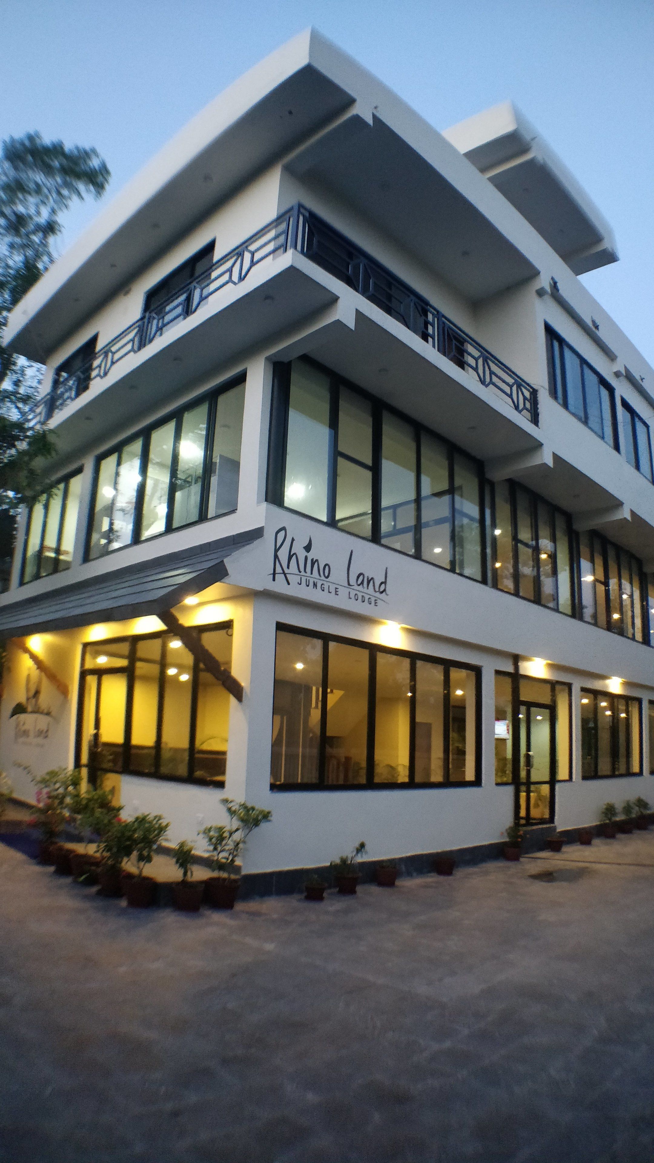 A two-story building with large windows and a sign that reads "Rhino Land Jungle Lodge".