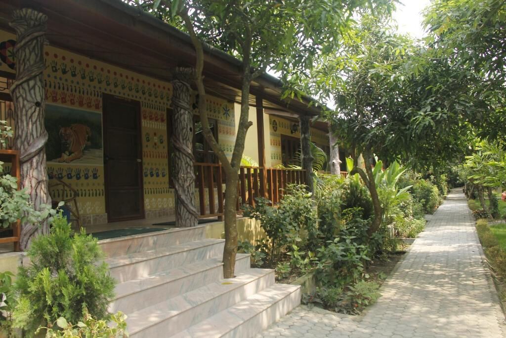 Un bâtiment traditionnel avec un porche carrelé, des marches et un chemin bordé de verdure.
