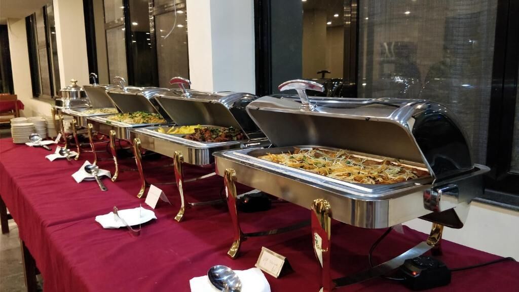 Dispositiu de buffet amb diverses zones de servei, cadascuna amb una safata de menjar coberta i una cullera per servir.