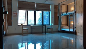 A room with a large window, a table, two chairs, a bunk bed, and a 'No Smoking' sign.