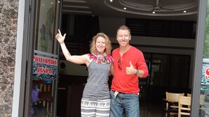 A man and a woman standing at the entrance of a building with a sign for motorbike rental.