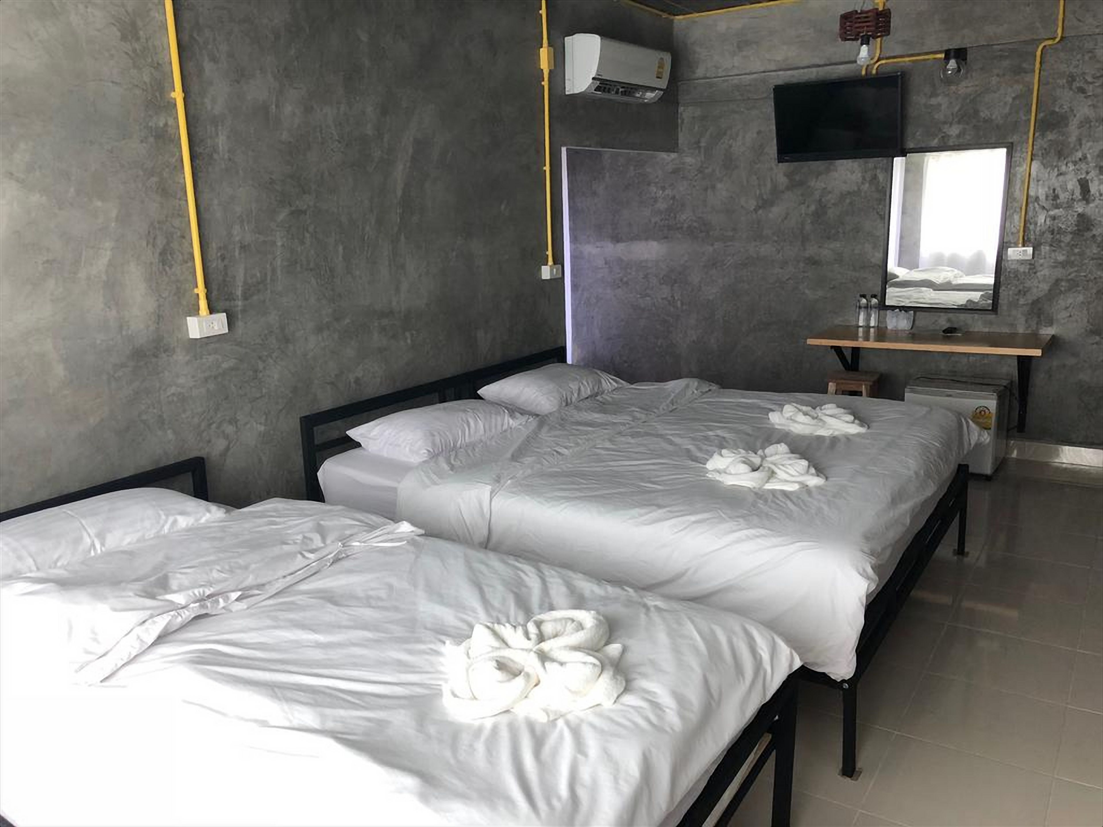 Habitación de hotel con dos camas, un escritorio, un televisor de pantalla plana y un equipo de aire acondicionado.