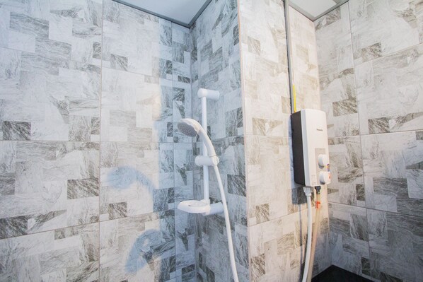 A shower with a handheld showerhead and a wall-mounted control panel. - The Sky Loft Hotel (Khlong Luang)
