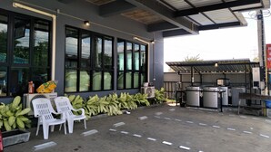 Un área de estar al aire libre con sillas y una mesa, un ventanal grande y equipo industrial.