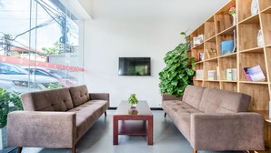 A modern living room with two sofas, a coffee table, and a bookshelf. - 7 Days Premium Hotel (Phnom Penh)