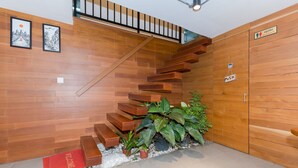 A wooden staircase with a handrail, a red mat at the bottom, and a sign indicating a push button. - 7 Days Premium Hotel (Phnom Penh)