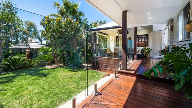 A modern house with a wooden deck, a glass door leading to a covered porch, and lush greenery. - Como Palm Retreat Rye Holiday Home with Pool (Rye)