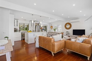 A modern living space with a kitchen, dining area, and a seating area with a sofa and coffee table.