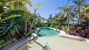 A clear pool surrounded by tropical plants and a wooden deck. - Como Palm Retreat Rye Holiday Home with Pool (Rye)