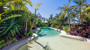 A clear pool surrounded by tropical plants and a wooden deck. - Como Palm Retreat Rye Holiday Home with Pool (Rye)