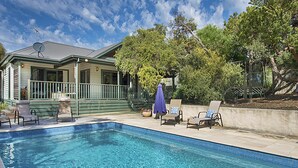 Une piscine avec des chaises longues et un espace patio couvert.