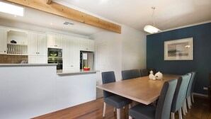 Una cucina moderna con mobili bianchi, un'isola in legno e un'area pranzo con tavolo e sedie.