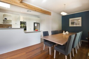 Een moderne keuken met witte kasten, een houten eiland en een eethoek met een tafel en stoelen.