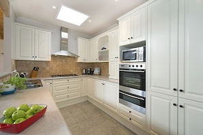 A kitchen with white cabinets, a gas stove, a microwave, and an oven. - Poolside Sorrento Pet Friendly (SORRENTO)