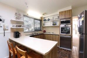 Een moderne keuken met een centraal eiland, houten kasten en inbouwapparatuur.