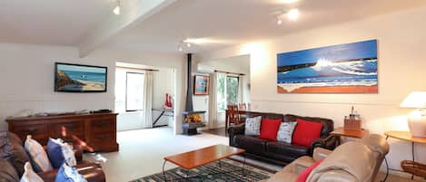 A spacious living room with a fireplace, leather sofas, a coffee table, and a large painting of a beach scene.