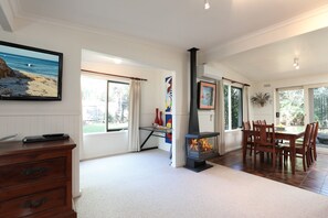 A spacious living area with a fireplace, dining table, and chairs. - Back Beach Hideaway Blairgowrie (BLAIRGOWRIE)