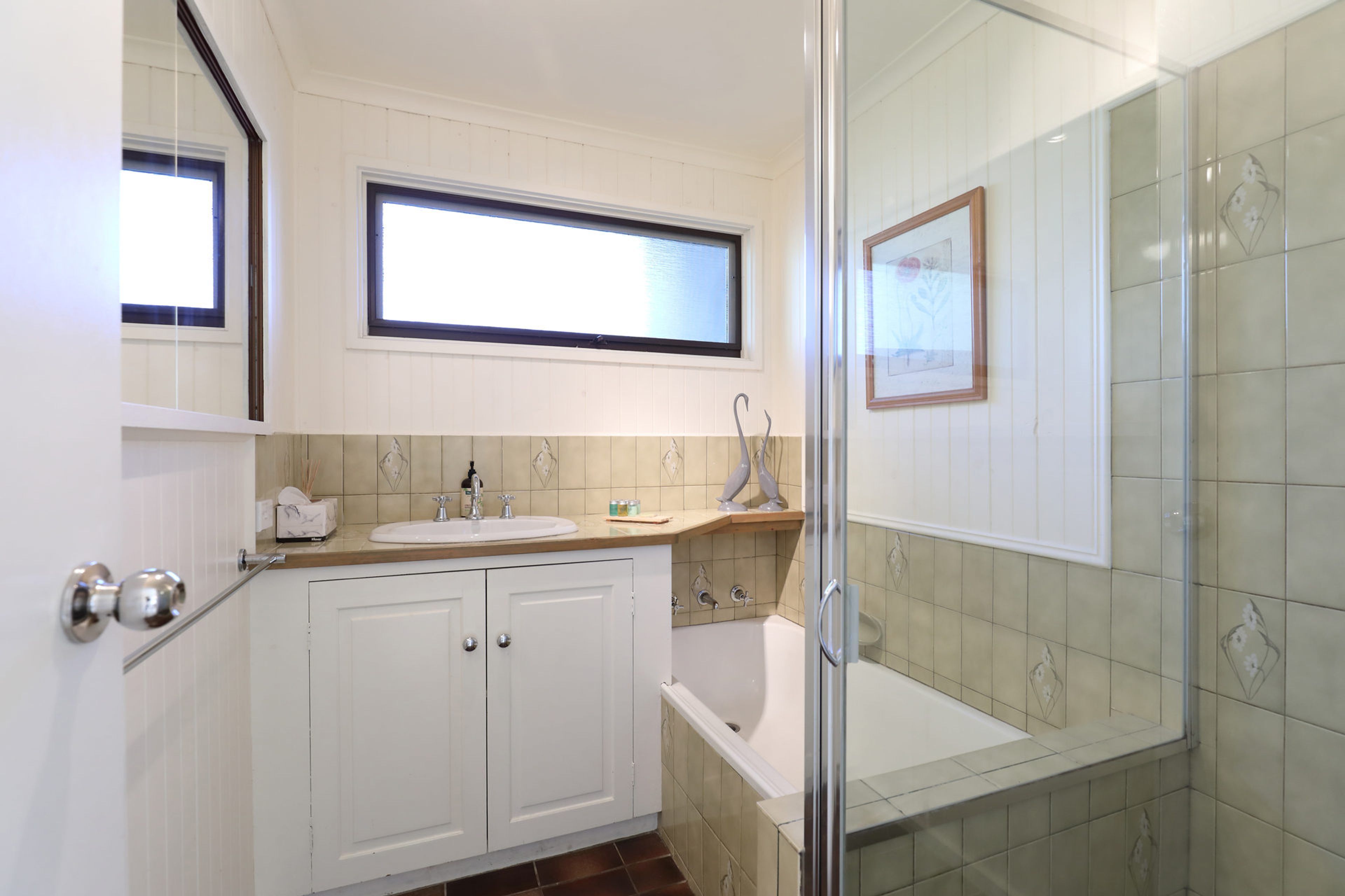 A bathroom with a white vanity, a bathtub, and a shower area.