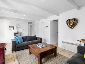 A modern living room with a grey sofa, a wooden coffee table, and a heart-shaped wall decoration. - Quarterdeck Portsea Coastal Pet Friendly Escape (PORTSEA)