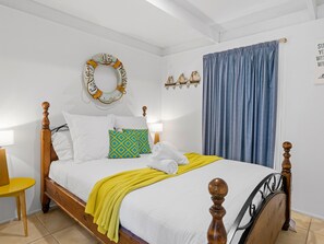 A neatly made bed with a yellow blanket, white pillows, and a wooden headboard. - Quarterdeck Portsea Coastal Pet Friendly Escape (PORTSEA)