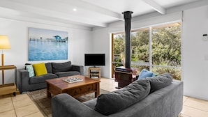 A modern living room with a sofa, coffee table, TV, and a fireplace.