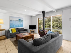 A modern living room with a sofa, coffee table, TV, and a fireplace. - Quarterdeck Portsea Coastal Pet Friendly Escape (PORTSEA)