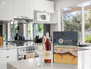 A kitchen with modern appliances, a wine bottle, and a brochure on the counter. - Quarterdeck Portsea Coastal Pet Friendly Escape (PORTSEA)