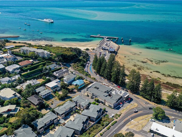Vista aérea de uma área residencial costeira com casas, uma praia e um píer.