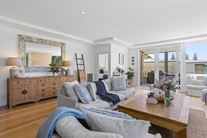 A spacious living room with a wooden coffee table, grey sofas, and a large mirror.
