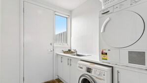 Una lavanderia funzionale con lavatrice, asciugatrice e una piccola finestra.