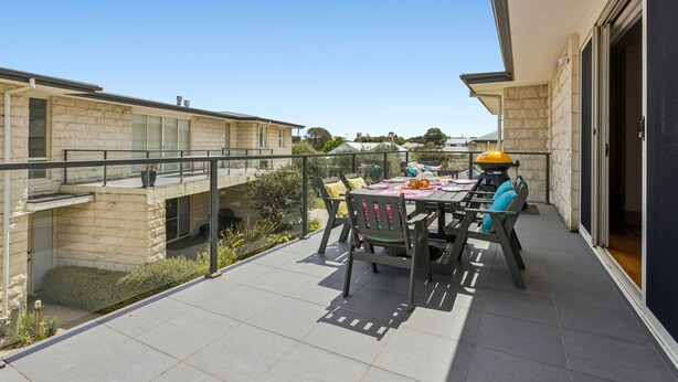 Un balcone con tavolo, sedie, un barbecue e vista sulle case vicine.
