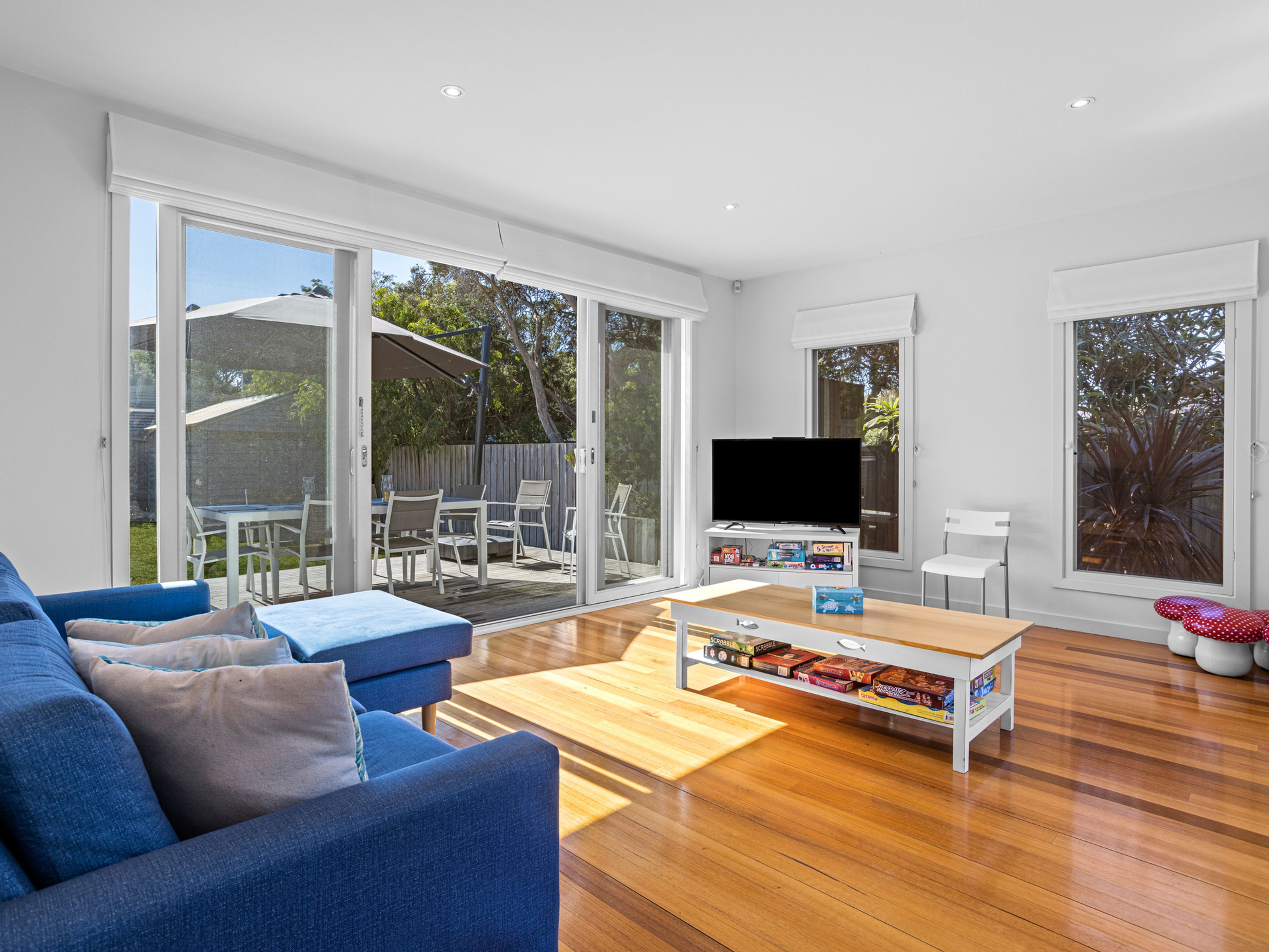 A modern living room with a blue sofa, wooden coffee table, and a flat-screen TV.