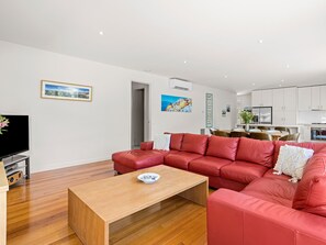 Un salon moderne avec un canapé en cuir rouge, une table basse en bois et un téléviseur à écran plat posé sur un meuble.