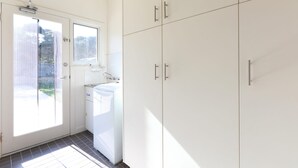 A kitchen with white cabinets, a window, and a washing machine. - Bluetopia Spacious Rye Retreat with Pool and BBQ (RYE)