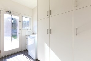 Une cuisine avec des meubles blancs, une fenêtre et un lave-linge.