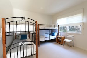 A room with bunk beds, a small table, a chair, and a window with a view. - Bluetopia Spacious Rye Retreat with Pool and BBQ (RYE)