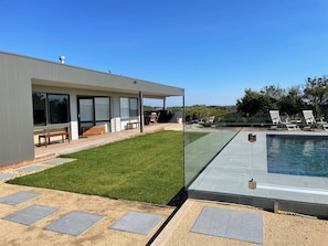 A modern house with a swimming pool, a patio with seating, and a well-maintained lawn.