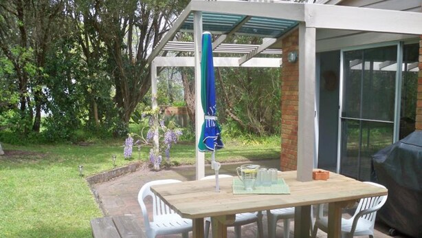 An outdoor patio with a wooden table and chairs, a covered seating area, and a grill. - Blairgowrie Relaxation (BLAIRGOWRIE)
