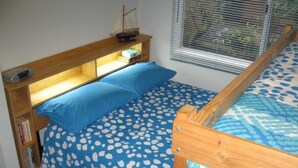 A bunk bed with a blue bedspread and a wooden headboard with shelves. - Blairgowrie Relaxation (BLAIRGOWRIE)