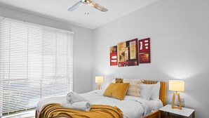 A bedroom with a bed, bedside tables, a ceiling fan, and artwork on the wall. - Diamond View Sorrento Holiday Home with Pool (Sorrento)