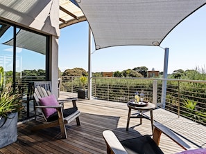 An outdoor deck with wooden furniture, a table with a bottle, and a view of the surrounding landscape. - Diamond View Sorrento Holiday Home with Pool (Sorrento)
