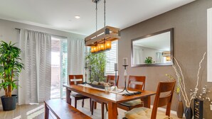 A dining area with a wooden table, chairs, and a hanging light fixture. - 1000 MBPS Fast Wifi★Model Home★Luxury Family Retreat 5B/4b (Jurupa Valley)