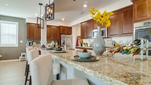 A modern kitchen with granite countertops, wooden cabinets, and a central island with seating. - 1000 MBPS Fast Wifi★Model Home★Luxury Family Retreat 5B/4b (Jurupa Valley)