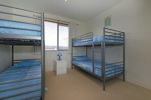 A dormitory room with bunk beds, a small white nightstand, and a window with blinds. - KaniCoast  Sorrento holiday home with Spa (SORRENTO)