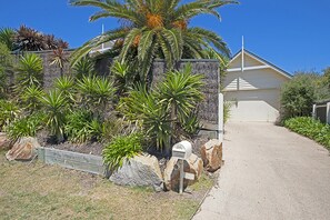 A residential property with a stone wall, palm trees, and a mailbox.