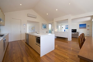 Una cocina moderna con una isla central, suelo de madera y un comedor con mesa y sillas.