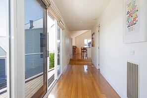 A spacious hallway with wooden flooring, large sliding glass doors, and a view of the outdoors.