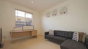 A modern living room with a desk, a leather sofa, and artwork on the walls.